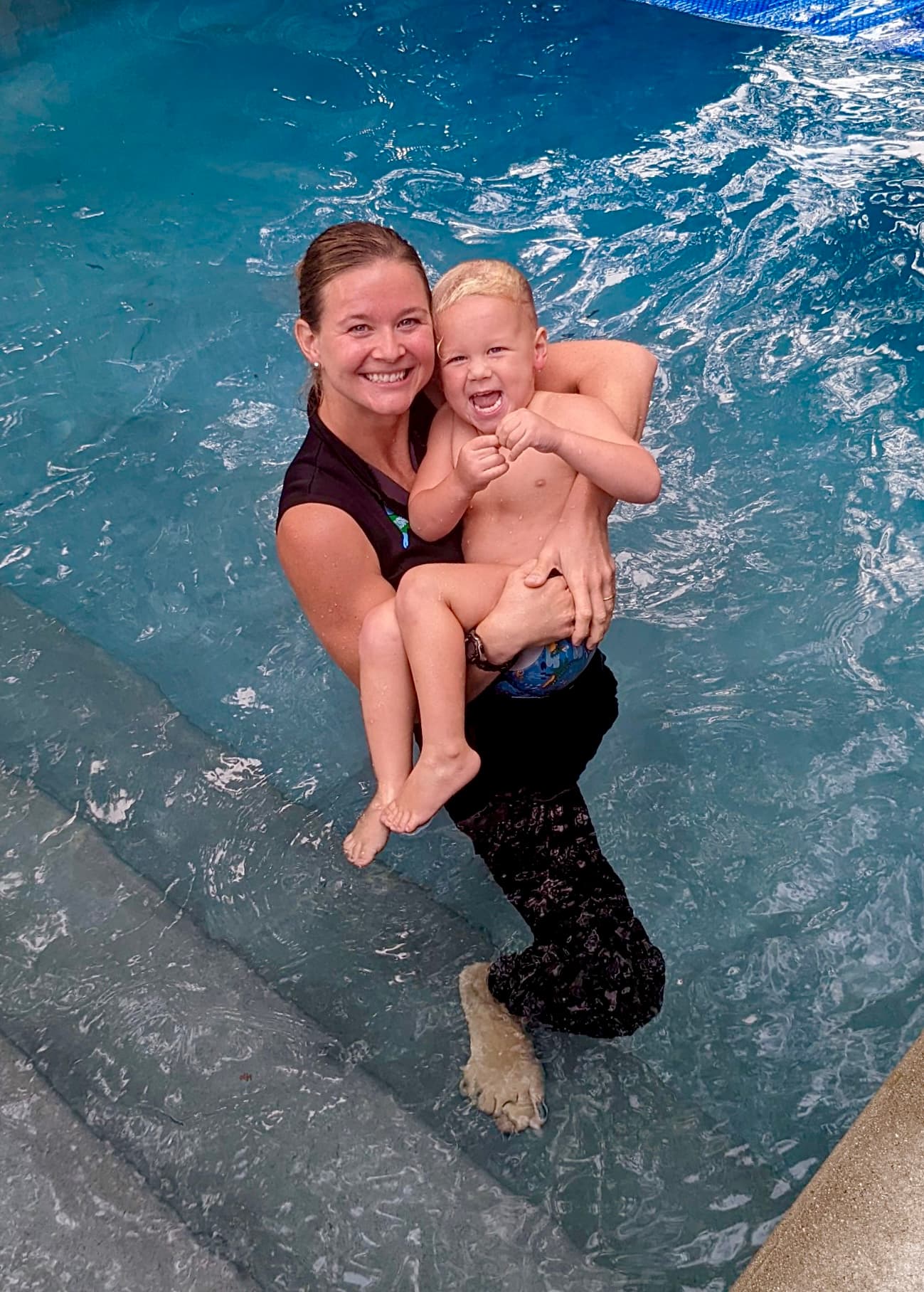 ISR instructor holding a smiling child during a pool lesson