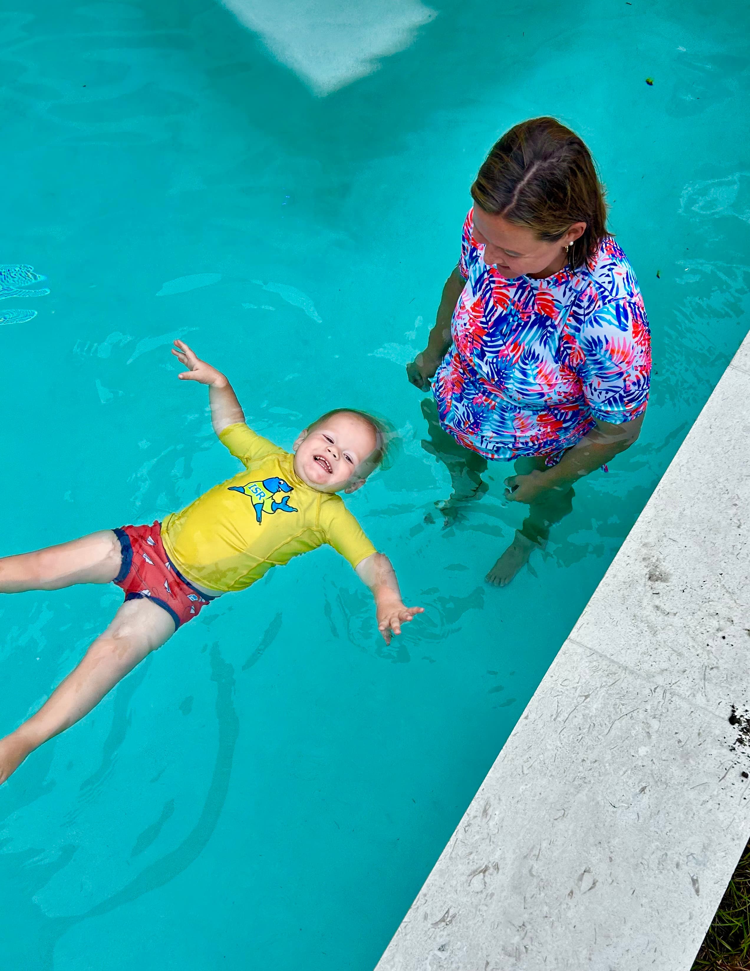 Instructor smiling beside a child practicing a calm float